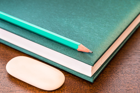 Book with a pencil and eraser on the tableの写真素材