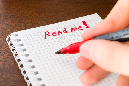 Read me sign in the notebook by red marker in the handの写真素材