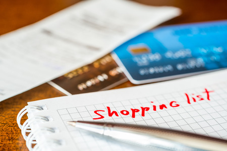 Shopping list, a notebook with shopping list and a credit cards with a check on the tableの写真素材