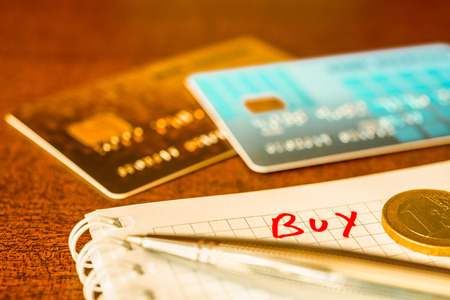 What to buy, ideas for shopping, credit cards with a pen on the table. In yellow tonesの写真素材