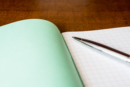 Pen and an exercise book on a wooden tableの写真素材