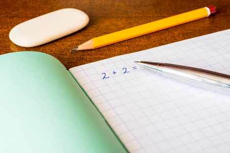 Studying in the school, solving mathematical problems, a pencil and eraser on the tableの写真素材