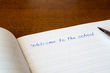 Welcome to the school, an exercise book and pen on the wooden tableの写真素材