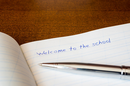 Welcome to the school, an exercise book and pen on the wooden tableの写真素材
