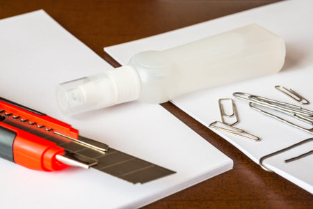 Stationery on the desk in the office, a knife on the paper with a clips. Focus on the knife