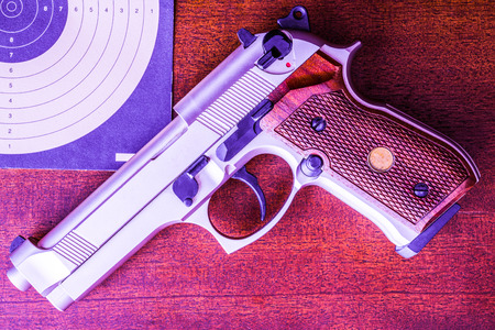 Target shooting, the gun and the target on the table. Top view, in blue tonesの写真素材