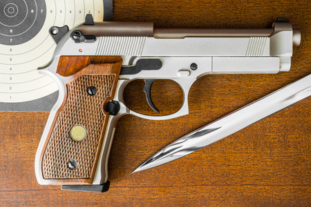 Target shooting, the gun and the target with the knife on the table. Top viewの写真素材