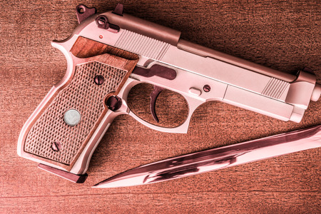 The knife and the pistol on the table. Top view, in red tonesの写真素材