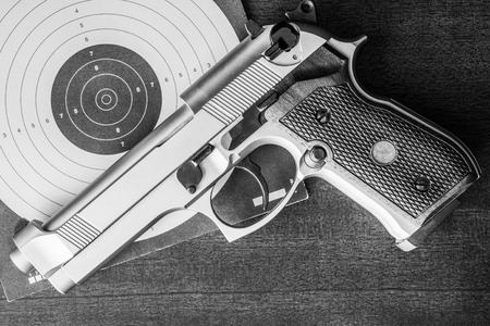 Target shooting, the gun and the target on the table. Top view, in black and white tonesの写真素材