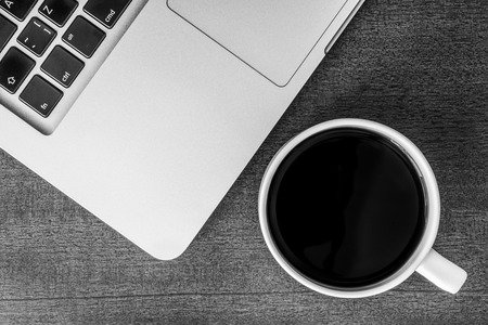 Work in the office, coffee cup with laptop  on the wooden table. In black and white tonesの写真素材