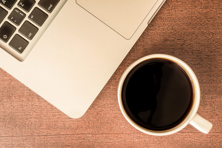 Work in the office, coffee cup with laptop  on the wooden table. In retro tonesの写真素材