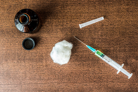 Cure the disease, a solution, and a syringe for injection with wadding on the table. In retro tonesの写真素材
