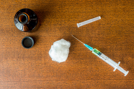 Cure the disease, a solution, and a syringe for injection with wadding on the tableの写真素材