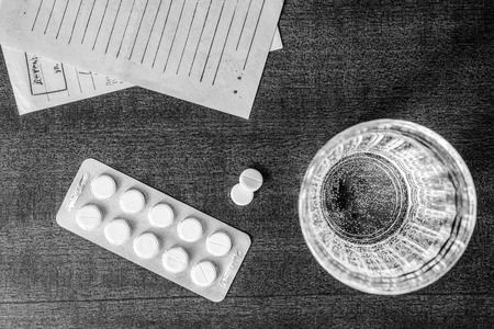 Cure the disease, tablets with a glass of water and prescriptions from the doctor on the table. In black and white tonesの写真素材