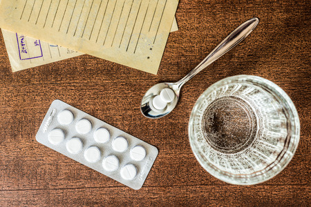Cure the disease, tablets in the spoon with a glass of water and prescriptions from the doctor on the table. In retro tonesの写真素材