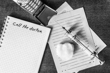 Call the doctor, a recipe and syringe injection with a phone on the table. In black and white tonesの写真素材