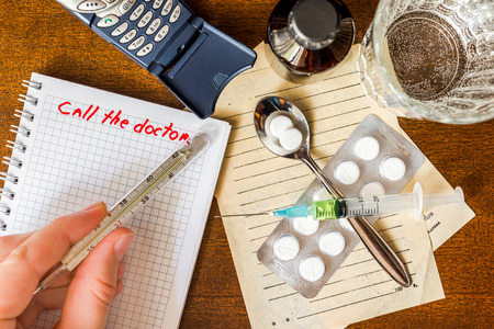Call the doctor, temperature measurement, a phone with a medical supplies on the tableの写真素材