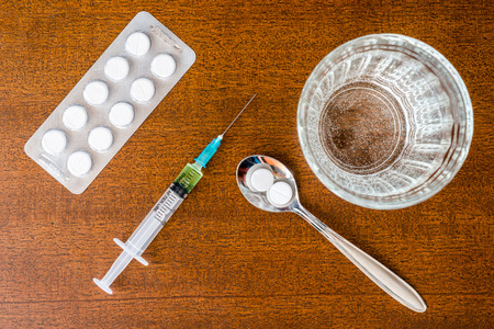 Cure the disease an injection syringe and take the pills in the spoonの写真素材