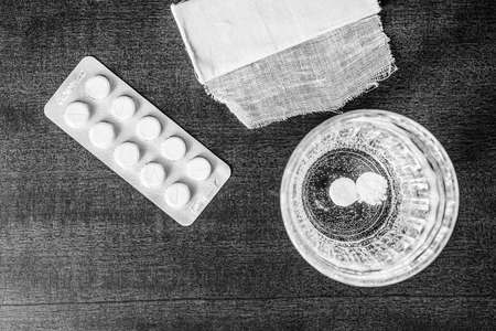 First aid medication dissolved in a glass of water and a bandage. Focus on the glass of waterの写真素材