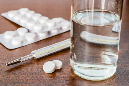 Cure the disease measure temperature and take the pills. Angle view focus on the pillsの写真素材