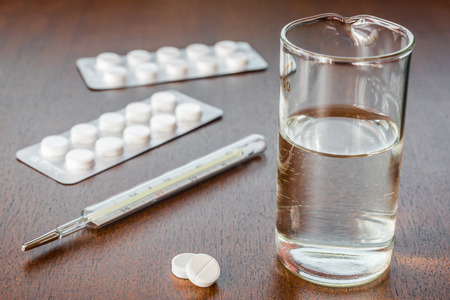 Cure the disease measure temperature and take the pills. Angle view focus on the pillsの写真素材