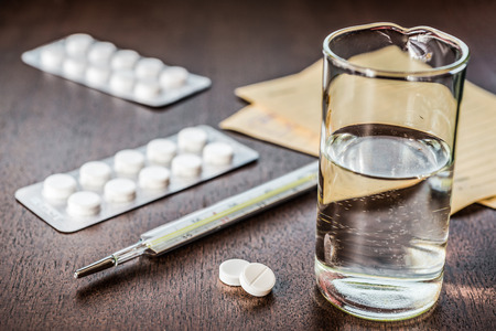 Cure the disease a tablets  with a glass of water and prescriptions from the doctor on the table. Angle view focus on the tablets in retro tonesの写真素材