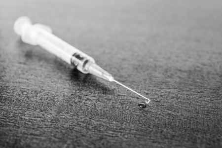 Medicine flows from the syringe and spread out on the table. Angle viewの写真素材
