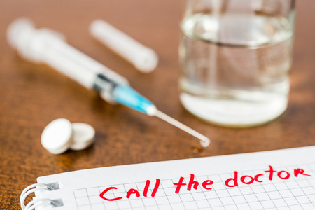 Call the doctor medicine flows from the syringe and spread out on the table. Angle view focus on the signの写真素材
