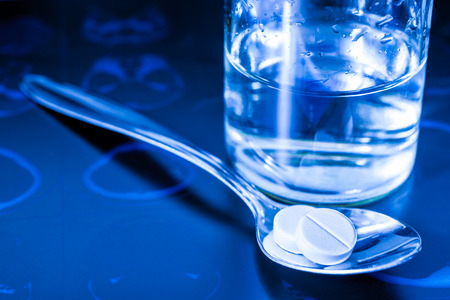 Xray examination a glass of the water and a pills in the spoon for treatment of disease. In blue tonesの写真素材