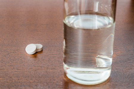 Cure the disease take the pills on the table and drinking water. Angle view focus on the pillsの写真素材