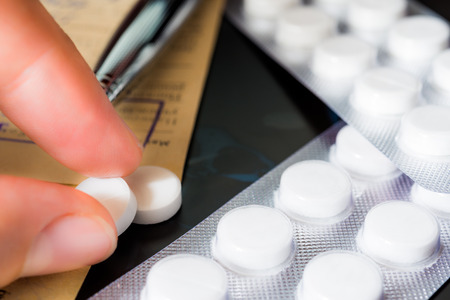X-ray examination, a prescription, hand takes pills, a pen on the recipe. Focus on the pillsの写真素材