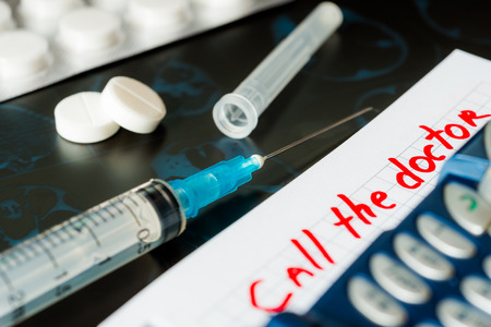 Call the doctor, x-rays and syringe injection with pills and phone on the tableの写真素材