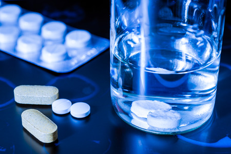 Take tablets, X-rays with pills and vitamins with a glass of water on the table. Focus on the glassの写真素材