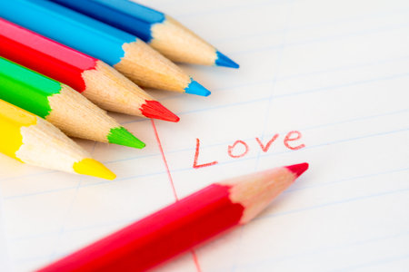 Word love written in a notebook with colored pencils, red pencil lying on the notebookの写真素材