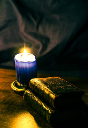Bible and old books and candle on a wooden table. Focus on the old books, image in yellow-blue toningの写真素材