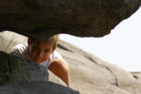 A young boy peeking between large rocks                   の写真素材