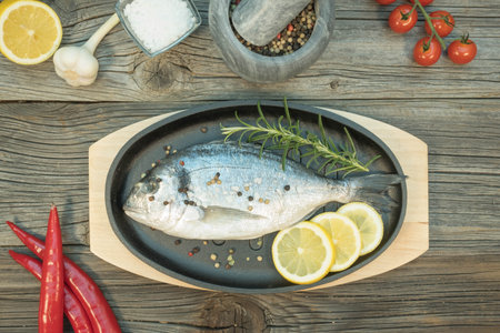 Fresh gilthead in pen on wooden background