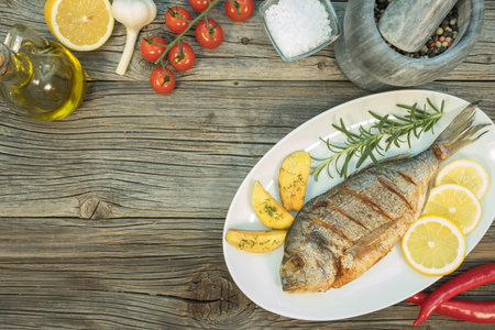 Grilled gilthead in pen on wooden background