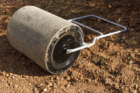 Old garden lawn roller on the ground under sunlightの写真素材