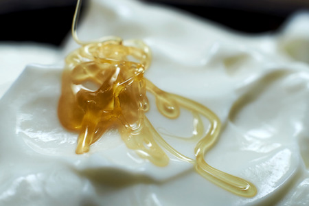 Honey flowing into a bowl with yogurt.の写真素材