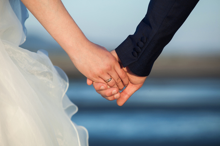 Wedding.Couple holding hands on the beach.の写真素材