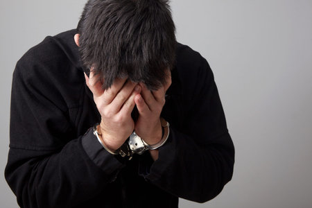 Closeup view of handcuffed man hidding his face.