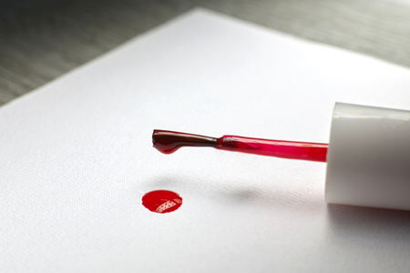 Brush of red nail polish spilled on a white paper.の写真素材