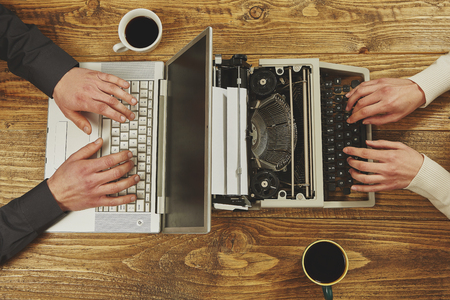 Woman writing on a typewriter and a man working on a laptop.Closeup to hands.Technological evolution.の写真素材
