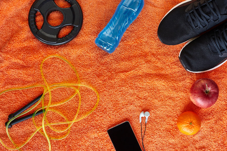 Fitness concept.Fruits, gym equipment and sport clothing on orange towel background.Healthy lifeslile.の写真素材
