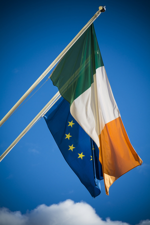 Irish and European Union flags together against blue skyの写真素材