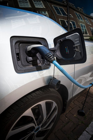 Electric car being recharged while parked on street