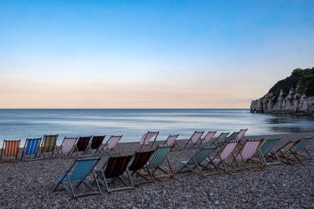 Line of deckchairs in calm bay on south coast of Englandの写真素材