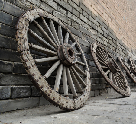 Ancient wooden wheels, standing in a row against the background of ancient brickwork, Xian City, Chinaの写真素材