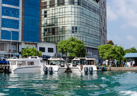 MALE, MALDIVES - November 17, 2017: Three speedboats, standing at the pier, near fresh fruit market in the background of skyscrapers, Male, Maldives, Indian Ocean. Travel and tourism conceptのeditorial素材